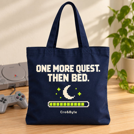 One More Quest. Then Bed. — Tote Bag — styled product photo with matching original PlayStation console and controller