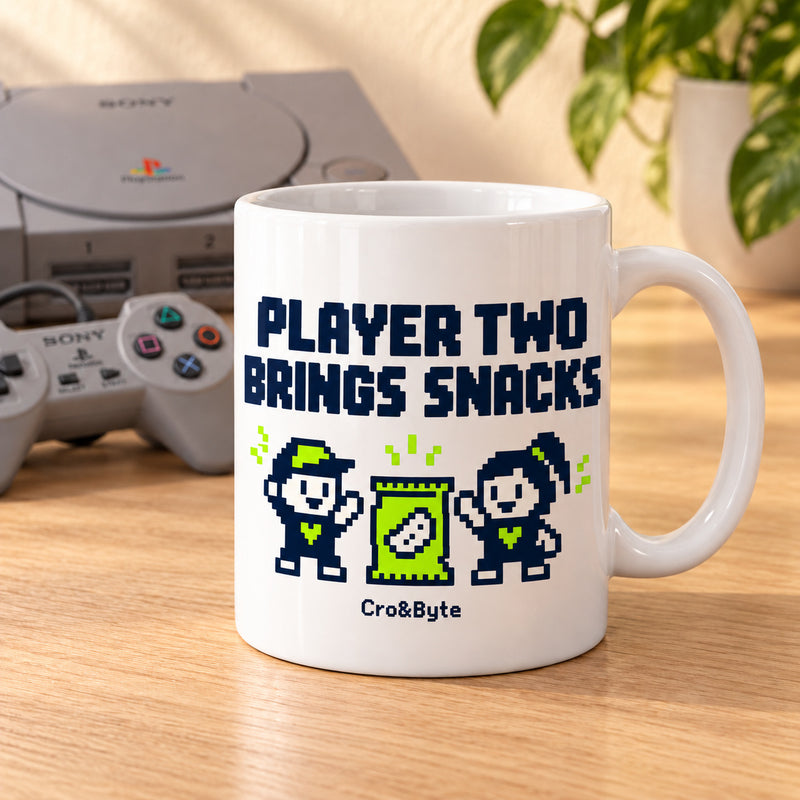 Player Two Brings Snacks — Mug — styled product photo with matching original PlayStation console and controller