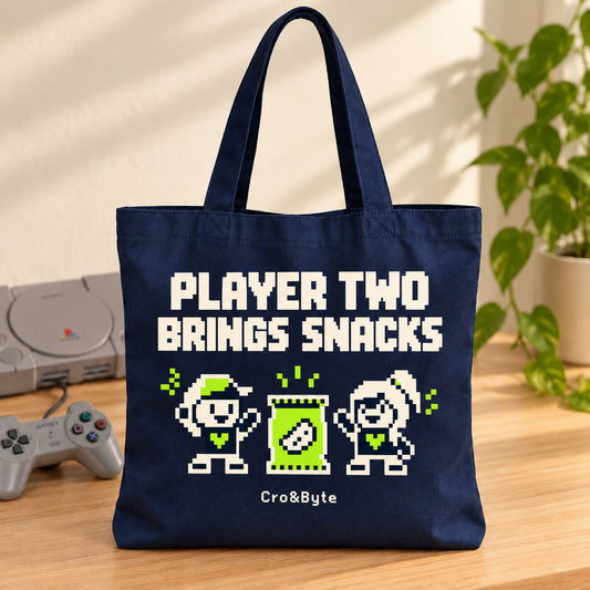 Player Two Brings Snacks — Tote Bag — styled product photo with matching original PlayStation console and controller